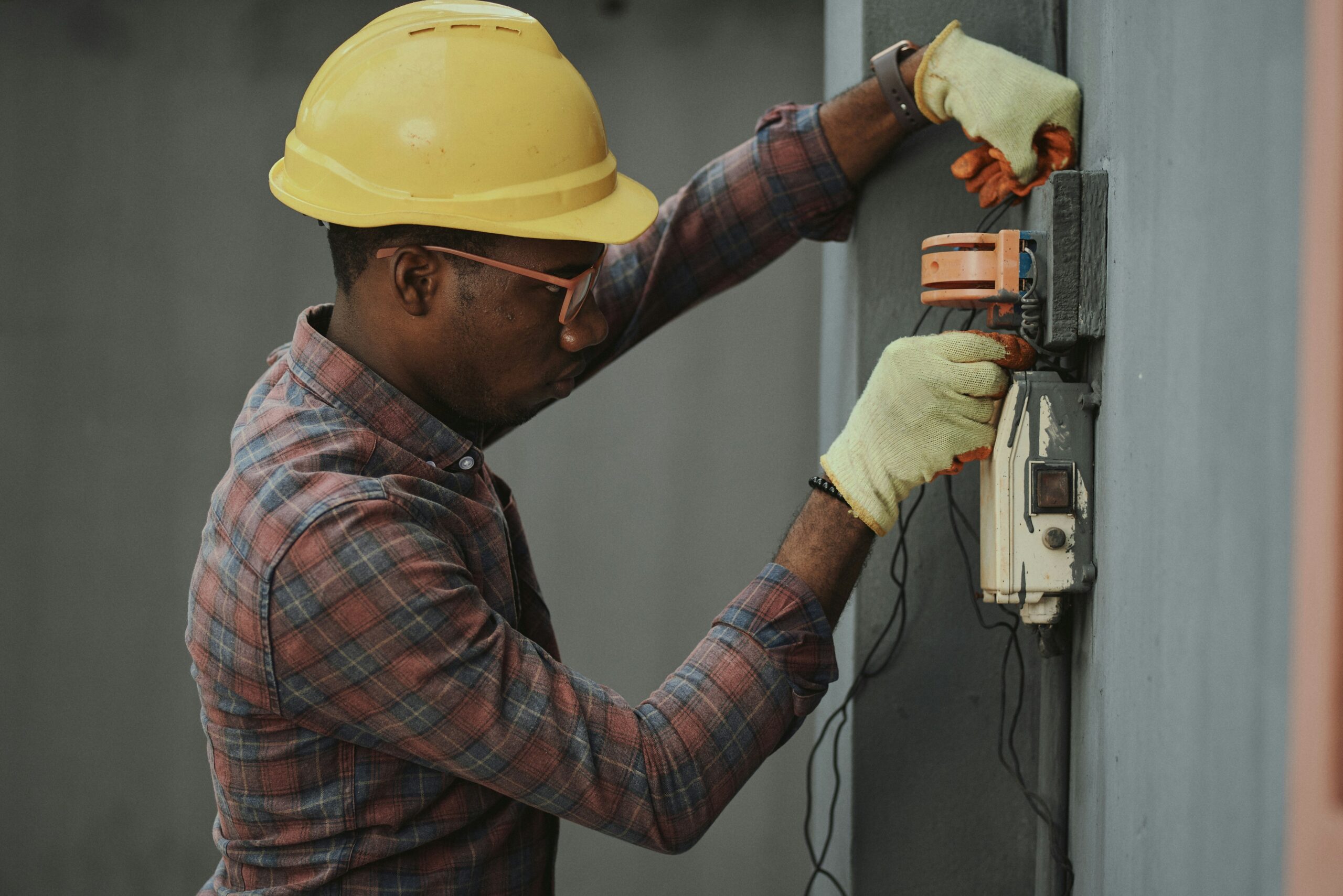 Man working on an electrical box with tools and safety equipment